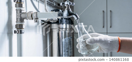 Laboratory technician collecting water sample from filtration system into flask Laboratory technician collecting water sample from filtration system into flask 140861168