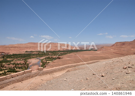 The vast red clay desert stretches out beneath the blue sky near Ait Benhaddou, Morocco. The vast red clay desert stretches out beneath the blue sky near Ait Benhaddou, Morocco. 140861946