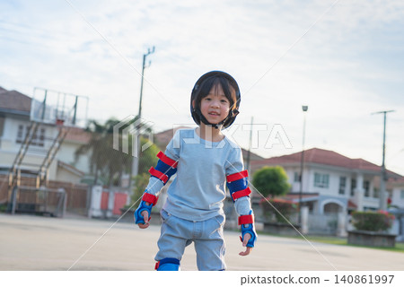 Active Asian little boy riding inline skates on an outdoor sports court during beautiful golden hour. Active Asian little boy riding inline skates on an outdoor sports court during beautiful golden hour. 140861997