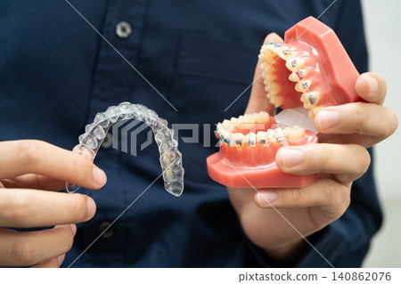 Man holding invisible aligner orthodontic retainer for dental teeth straightening. Man holding invisible aligner orthodontic retainer for dental teeth straightening. 140862076