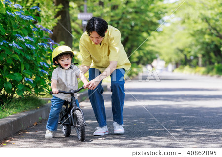 A boy riding a bicycle with his dad A boy riding a bicycle with his dad 140862095