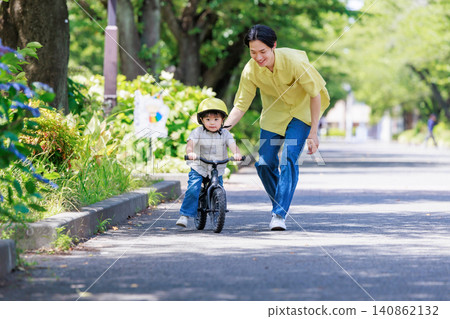 A boy practicing riding a bicycle with his dad. A boy practicing riding a bicycle with his dad. 140862132