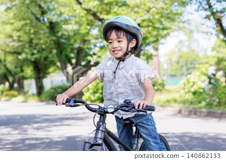 A young elementary school boy playing energetically on his bicycle. A young elementary school boy playing energetically on his bicycle. 140862133
