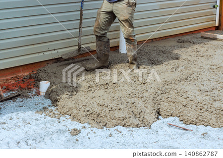 Worker stands on wet concrete while preparing to finish cement slab surface at construction site Worker stands on wet concrete while preparing to finish cement slab surface at construction site 140862787