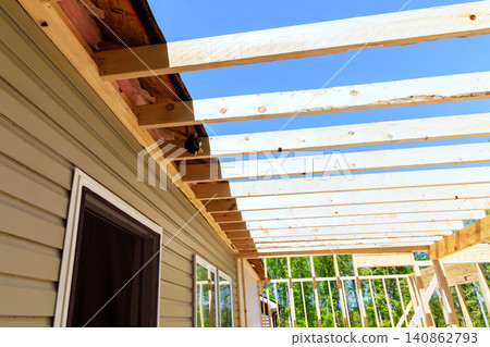 Workers build wooden frame for new beams structure next to house with frameworks Workers build wooden frame for new beams structure next to house with frameworks 140862793