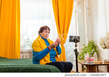 Elderly woman hosting a beauty livestream focused on skincare and cosmetic trends. Content creator concept. Active senior participation in online communities. Wide shot Elderly woman hosting a beauty livestream focused on skincare and cosmetic trends. Content creator concept. Active senior participation in online communities. Wide shot 140862847