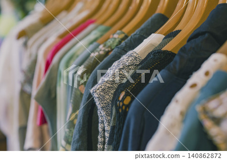 復古服飾店的衣架上整齊地掛著色彩鮮豔的針織衫和開襟衫。 復古服飾店的衣架上整齊地掛著色彩鮮豔的針織衫和開襟衫。 140862872