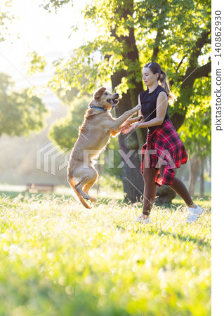 Woman plays with dog in sunny park during afternoon Woman plays with dog in sunny park during afternoon 140862930