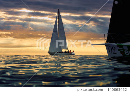 A lot of sailing boats are in sailing regatta in the Gulf of Finland at sunset, Russia, St.Petersburg, hot race of several yachts, teamwork, yachtsman A lot of sailing boats are in sailing regatta in the Gulf of Finland at sunset, Russia, St.Petersburg, hot race of several yachts, teamwork, yachtsman 140863432