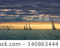 A lot of sailing boats are in sailing regatta in the Gulf of Finland at sunset, Russia, St.Petersburg, hot race of several yachts, teamwork, yachtsman 140863444