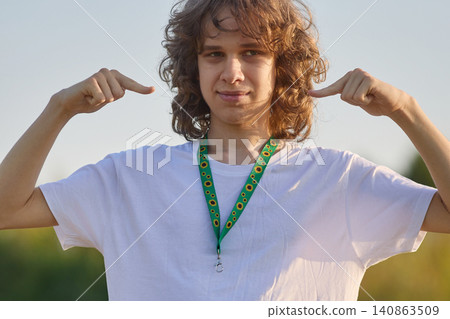 Young man pointing to invisible disability sunflower lanyard 140863509