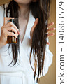 Woman Applying Hair Treatment Spray To Wet Hair During Beauty Routine, Healthy Hair Care, Home Self Care And Beauty Wellness Concept 140863529