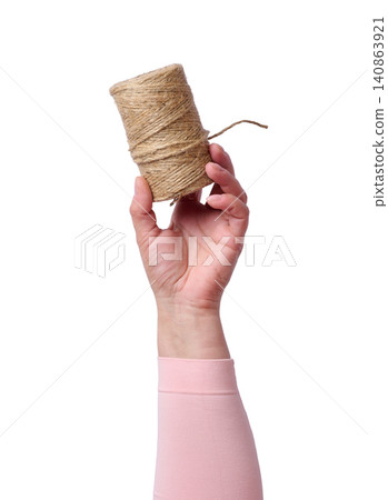 A woman's hand in a pink sleeve holds a jute rope in a skein on an isolated background A woman's hand in a pink sleeve holds a jute rope in a skein on an isolated background 140863921