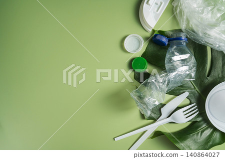 Plastic waste items on green background with copy space, recycling and environmental pollution concept Plastic waste items on green background with copy space, recycling and environmental pollution concept 140864027