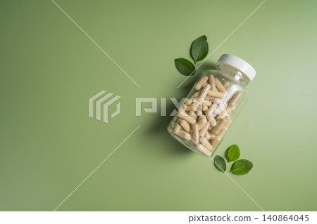 Herbal supplement capsules in bottle with leaves with green background, natural wellness concept Herbal supplement capsules in bottle with leaves with green background, natural wellness concept 140864045