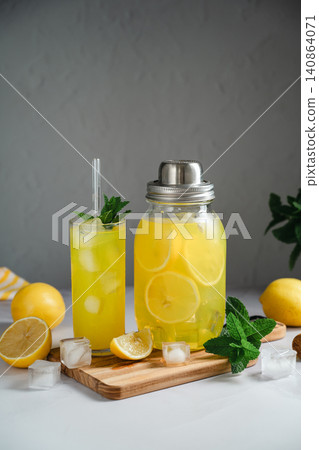 Homemade lemonade with fresh mint and ice cubes, served in drinking glass and jar, summer beverage concept Homemade lemonade with fresh mint and ice cubes, served in drinking glass and jar, summer beverage concept 140864071
