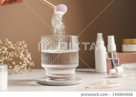 Collagen peptides supplement preparation with powder added to glass of water, copy space Collagen peptides supplement preparation with powder added to glass of water, copy space 140864086