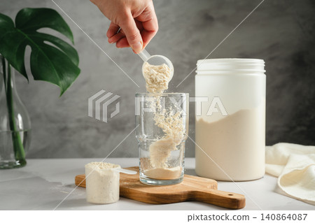 Protein powder being poured into glass, sports nutrition concept Protein powder being poured into glass, sports nutrition concept 140864087
