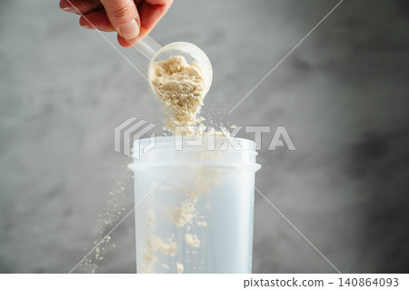 Adding whey protein powder to shaker bottle for fitness shake preparation Adding whey protein powder to shaker bottle for fitness shake preparation 140864093