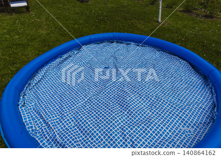 Repairing a hole in a blue swimming pool liner in backyard on a sunny day Repairing a hole in a blue swimming pool liner in backyard on a sunny day 140864162