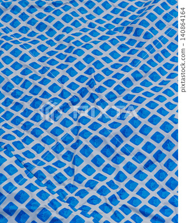 Repairing a hole in an above ground pool liner during summer maintenance Repairing a hole in an above ground pool liner during summer maintenance 140864164