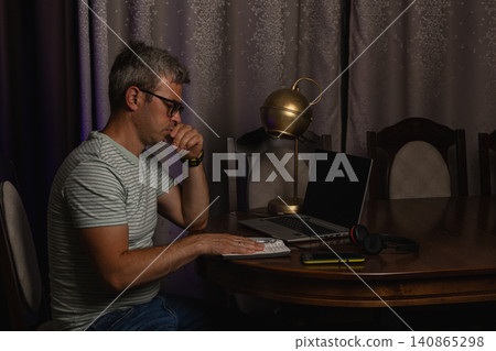 Freelancer working late at a home office desk with a laptop 140865298