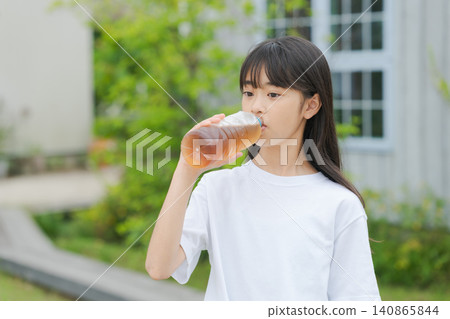 A girl drinking barley tea from a plastic bottle. A girl drinking barley tea from a plastic bottle. 140865844