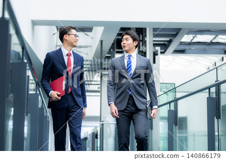 一群身著西裝的商務人士正走在辦公走廊。 一群身著西裝的商務人士正走在辦公走廊。 140866179