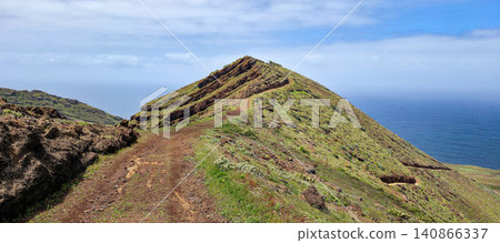 Scenic view of a winding dirt path leading up a green hillside overlooking the ocean in a coastal landscape. Northern viewpoint of La Palma Island Cruz de La Centinela. High quality photo Scenic view of a winding dirt path leading up a green hillside overlooking the ocean in a coastal landscape. Northern viewpoint of La Palma Island Cruz de La Centinela. High quality photo 140866337