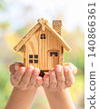 Hands holding a miniature model of a house against a blurred background 140866361