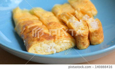 roll omelette stuffed with chesse and rice on blue plate, delicious food in the morning roll omelette stuffed with chesse and rice on blue plate, delicious food in the morning 140866416