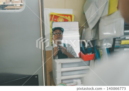 超市經理在後屋的鏡子前檢查領帶。 超市經理在後屋的鏡子前檢查領帶。 140866773