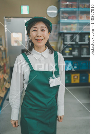 一位五十多歲的女員工面帶微笑地站在超市的後倉。 一位五十多歲的女員工面帶微笑地站在超市的後倉。 140867016