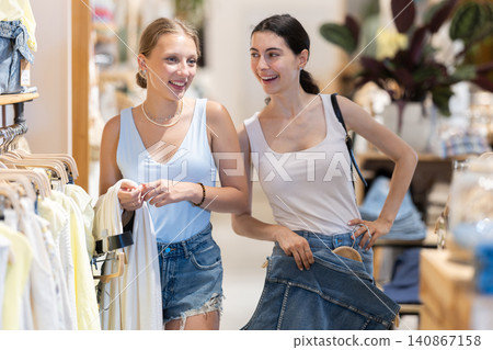 Two sisters girl chooses something in outlet clothing store Two sisters girl chooses something in outlet clothing store 140867158