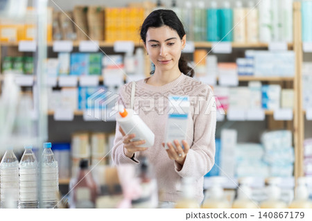 Girl in autumn clothes choosing skin cream at drugstore 140867179
