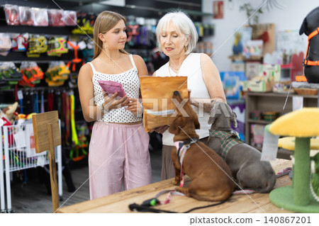 elderly woman stands in a pet store with a teenage girl and chooses food 140867201