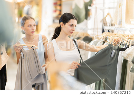 Woman choosing green pants on the background of a friend 140867215