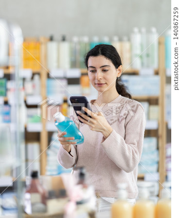 Young woman scanning qr code of mouthwash Young woman scanning qr code of mouthwash 140867259