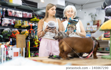 elderly woman stands in a pet store with a teenage girl and chooses food elderly woman stands in a pet store with a teenage girl and chooses food 140867290