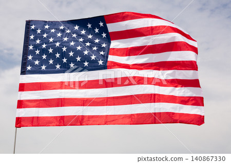 American flag flying on flagstaff against backdrop of cloudy sky American flag flying on flagstaff against backdrop of cloudy sky 140867330