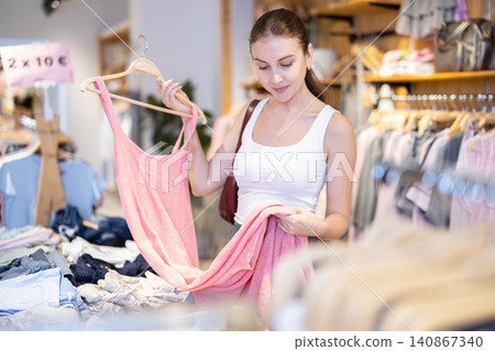 Girl customer chooses dress in branded store 140867340