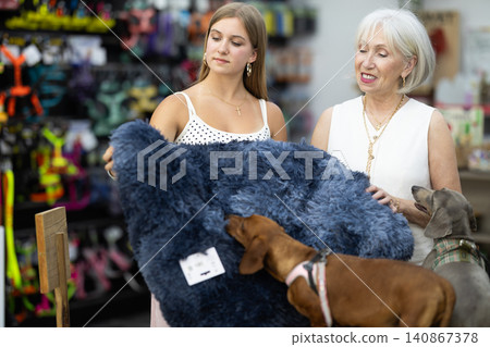 Girl and woman choosing blanket for two dogs in pet store Girl and woman choosing blanket for two dogs in pet store 140867378