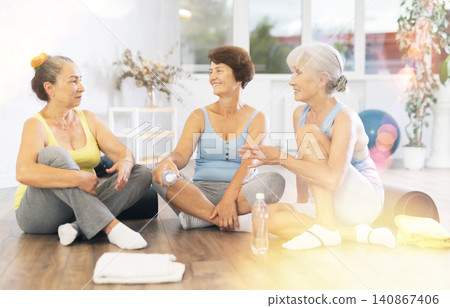 Group of elderly women in gym communicate after training and discuss plans for evening Group of elderly women in gym communicate after training and discuss plans for evening 140867406
