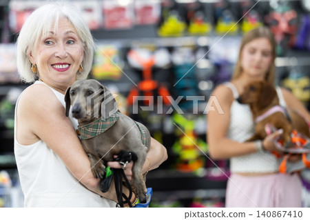 Elderly woman holding dog in her arms at pet store Elderly woman holding dog in her arms at pet store 140867410
