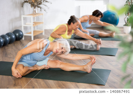 Mature lady performs Janu shirshasana 140867491