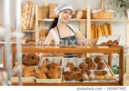 Young woman seller puts croissants in showcase 140867492