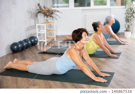 Group of elderly woman doing yoga on mat in studio Group of elderly woman doing yoga on mat in studio 140867538