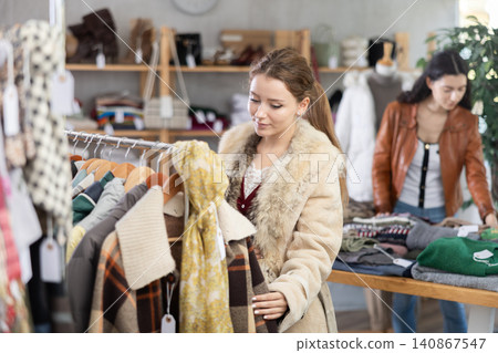 Young woman chooses outerwear in store Young woman chooses outerwear in store 140867547