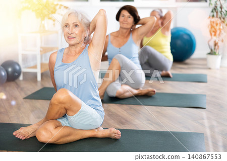 Senior lady performs cow head pose, Gomukhasana 140867553