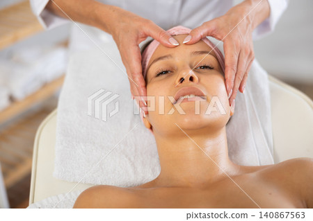 Young woman enjoying professional facial massage in beauty salon Young woman enjoying professional facial massage in beauty salon 140867563